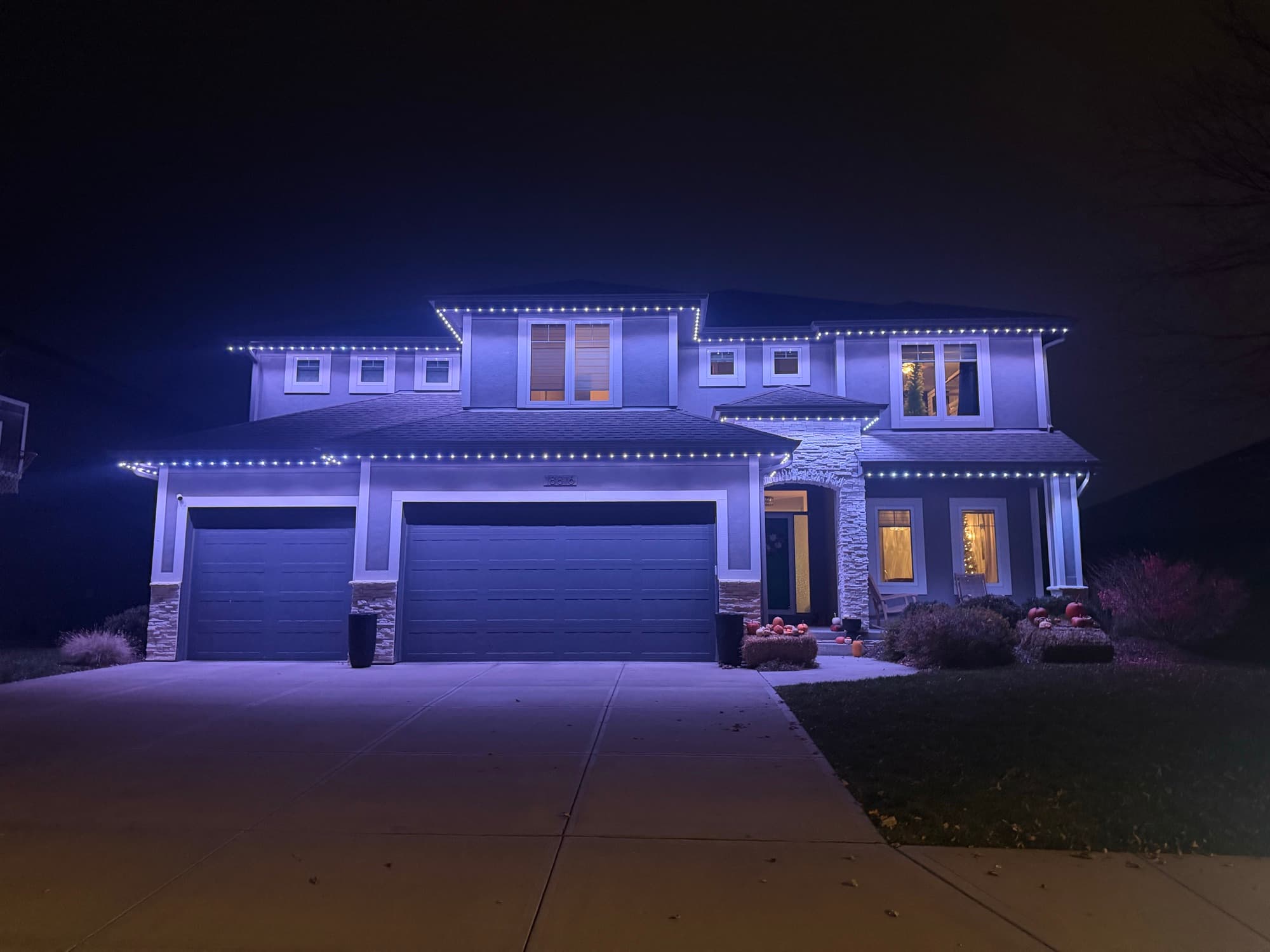 Two-story Omaha home outlined in crisp cool-white permanent roofline lighting at night.